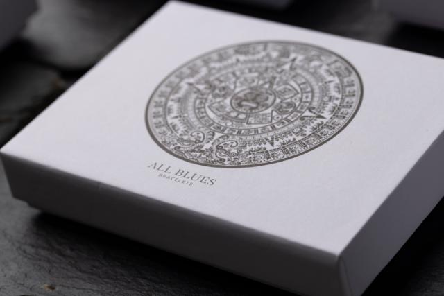 Ein grauer Deckel einer Schachtel mit einem aufwendigen kreisförmigen Muster und der Aufschrift