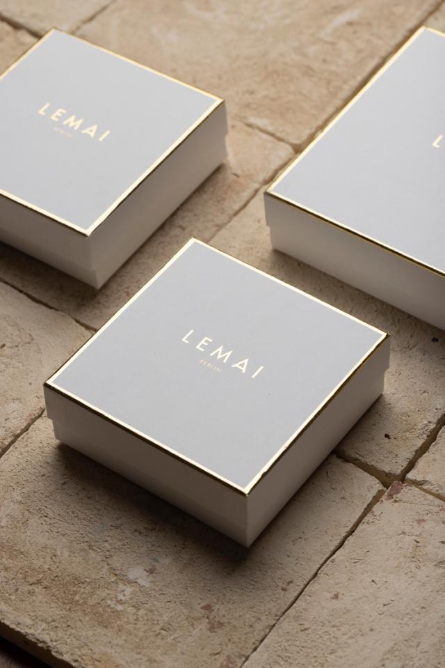 Drei quadratische, harte Schachteln mit goldener Heißfolienprägung des Logos