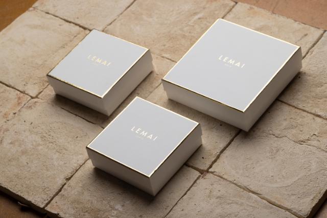 Drei quadratische, harte Schachteln mit goldener Heißfolienprägung des Logos