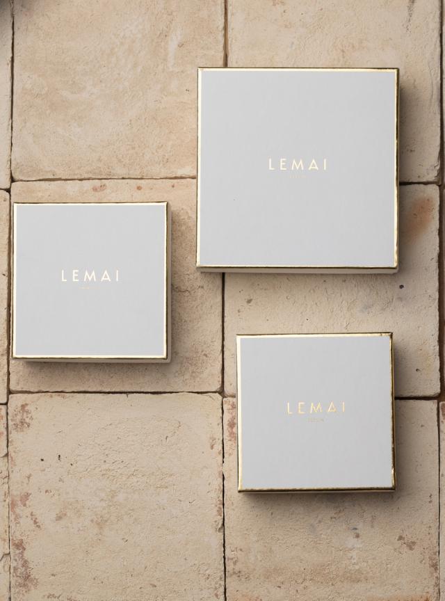 Drei quadratische, harte Schachteln mit goldener Heißfolienprägung des Logos